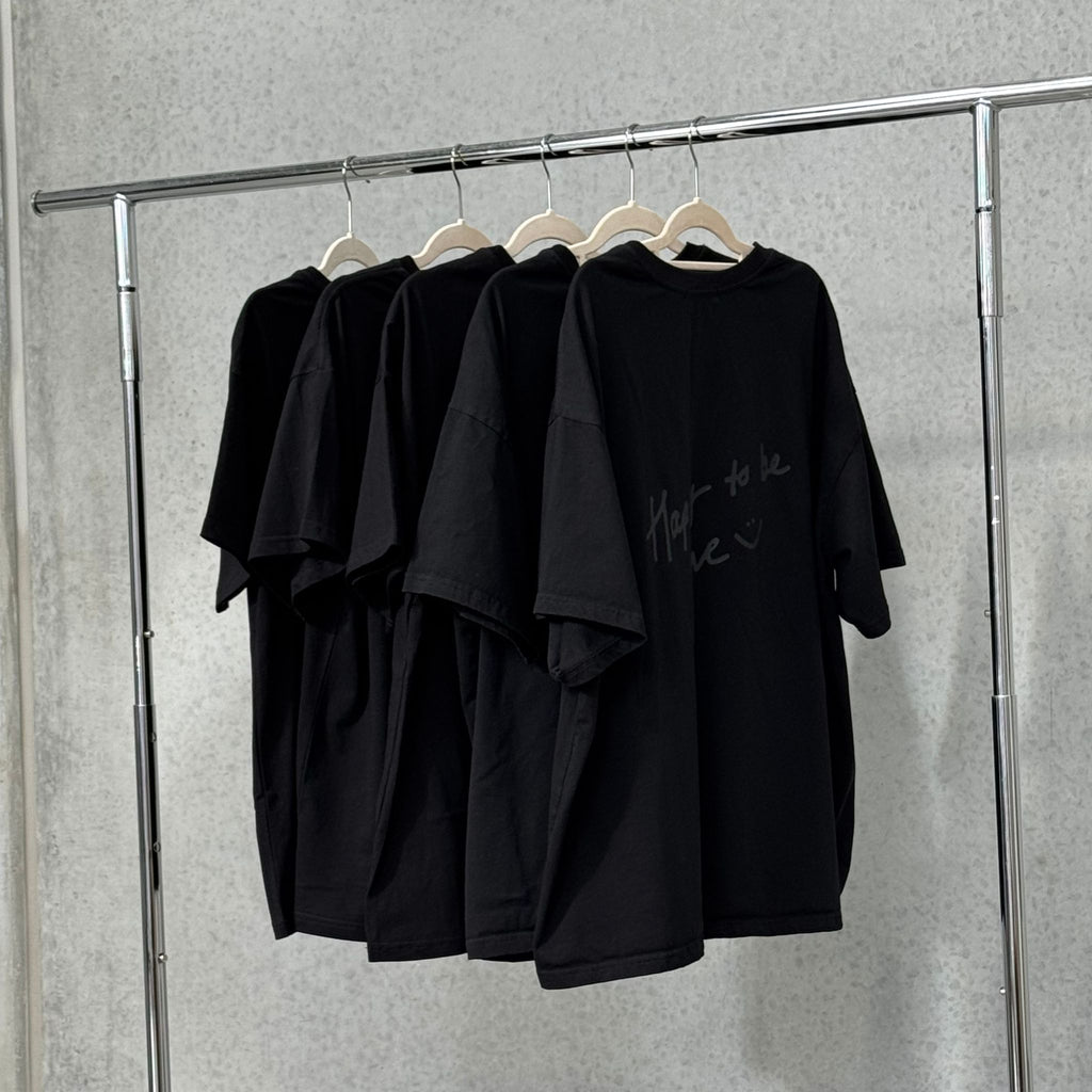 black happy to be here tee hanging on rack